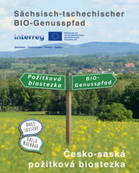 Wegweiser in ländlicher Landschaft mit den Beschriftungen „BIO-Genusspfad“ und „Požitková biostezka“ vor Wiesen und Hügeln – Hinweis auf den sächsisch-tschechischen BIO-Genusspfad.